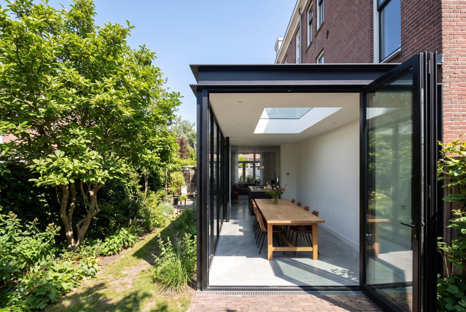 Black steel and glass rear extension opening onto a green city garden