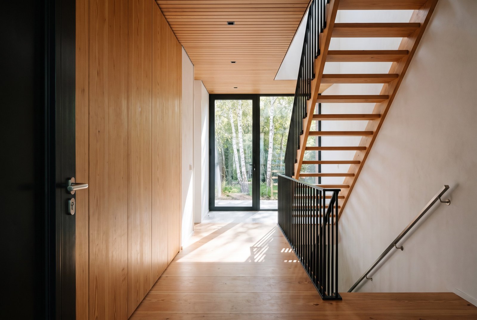 View from the entrance along Douglas fir joinery to a glass wall onto birches