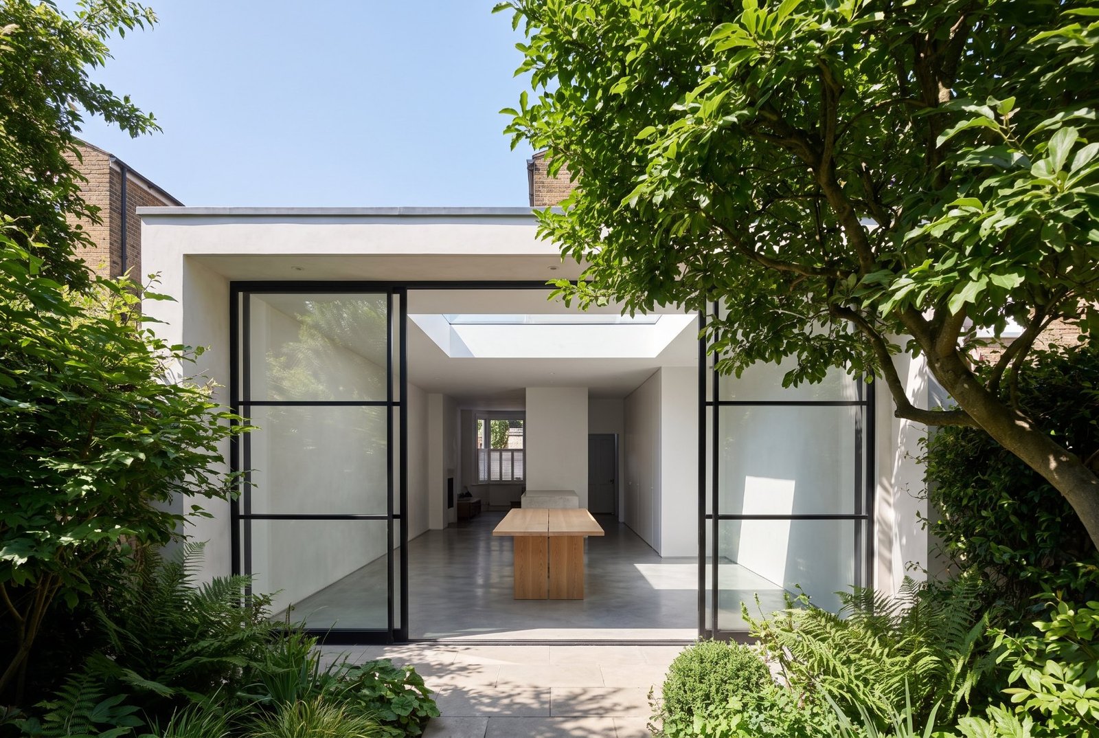 Black steel and glass extension opening onto a green garden